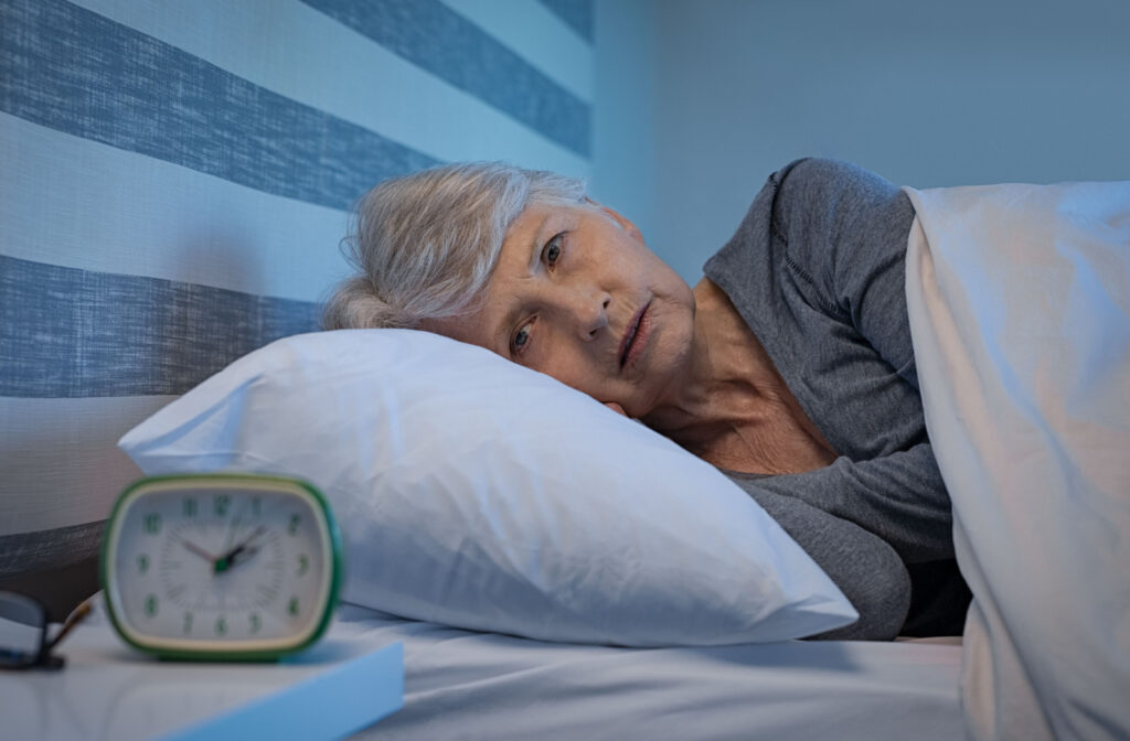 A senior woman lying alone in bed and unable to sleep.