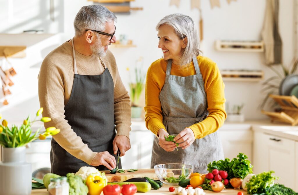 An older couple happily prepares a balanced meal together.
